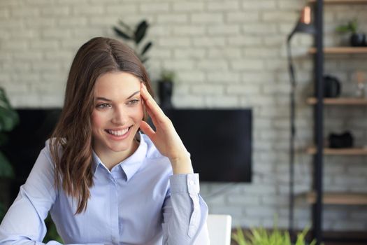 Smiling pretty woman sitting at table, looking at laptop screen. Happy entrepreneur reading message email with good news, chatting with clients online