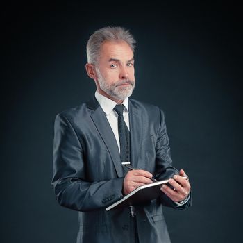 serious businessman signs a working document.isolated on black.