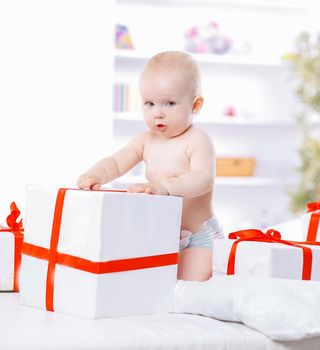 pretty baby plays with gift boxes.