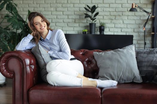 Beautiful young woman sitting on sofa, indoors