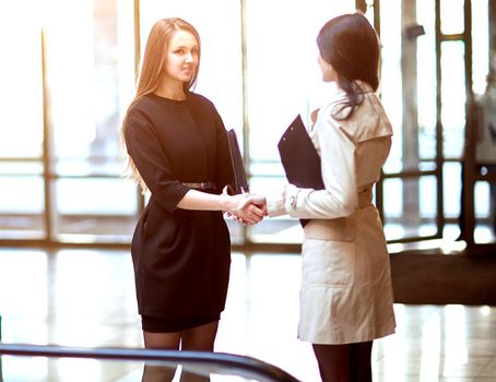 two businesswomen shaking hands in the office lobby. concept of partnership