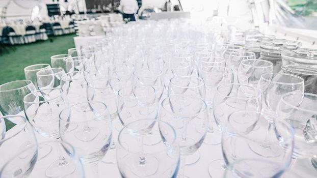 lots of empty glass glasses on the table in the restaurant . festive reception