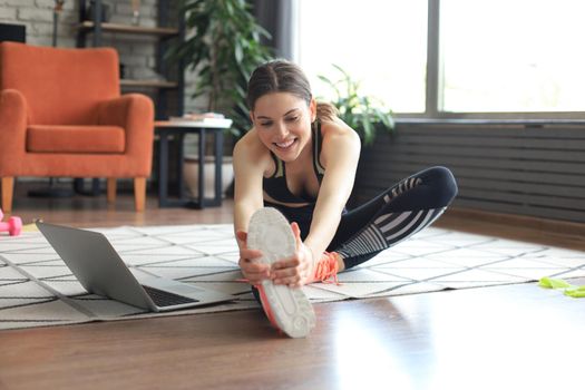 Fitness beautiful slim woman doing fitness stretching exercises at home in the living room. Stay at home activities. Sport, healthy lifestyle