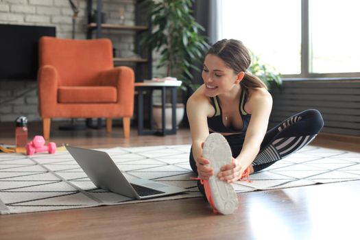 Fitness beautiful slim woman doing fitness stretching exercises at home in the living room. Stay at home activities. Sport, healthy lifestyle