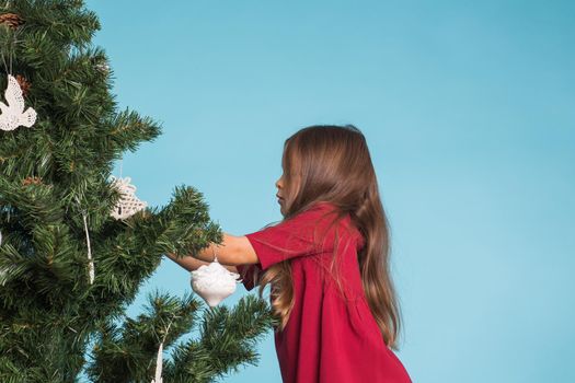 Christmas, childhood and people concept - little girl decorating the christmas tree.