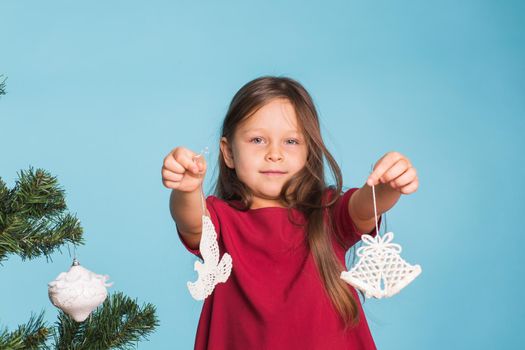 Christmas, childhood and people concept - little girl decorating the christmas tree.