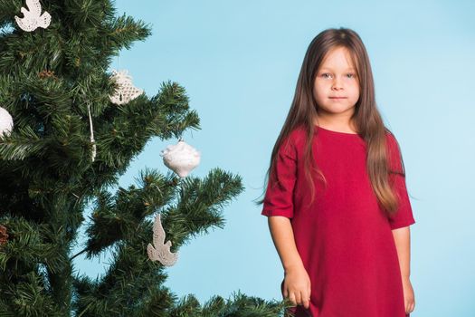 Little girl with christmas tree on blue background.