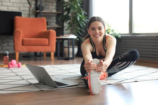 Fitness beautiful slim woman doing fitness stretching exercises at home in the living room. Stay at home activities. Sport, healthy lifestyle