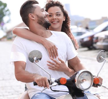 Young happy couple riding scooter together smiling