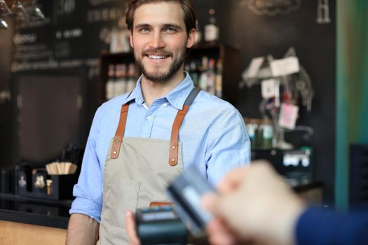 Customer using credit card for payment to owner at cafe restaurant, cashless technology