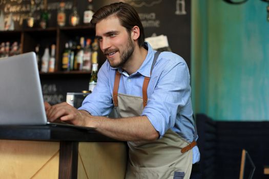 Restaurant manager working on laptop, counting profit