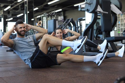 Attractive man and woman working in pairs performing sit ups in gym