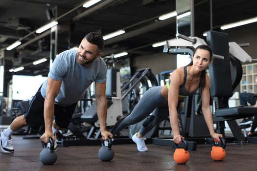 Sporty man and woman doing push-up in a gym