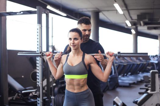 Man and woman with barbell flexing muscles in gym