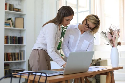 Two female collegues working with laptop and discussing new project