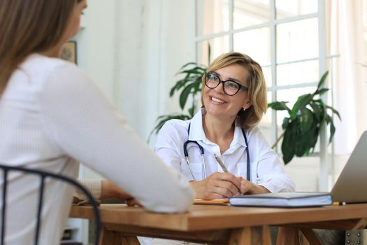 Middle aged female doctor therapist in consultation with patient in office