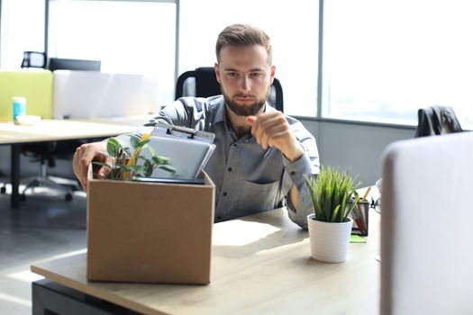 Sad dismissed worker are taking his office supplies with him from office