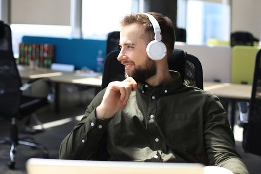 Happy modern business man working using laptop while sitting in the office