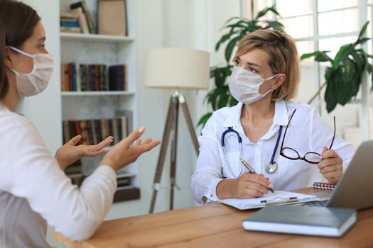 Middle aged female doctor therapist in consultation with patient in office