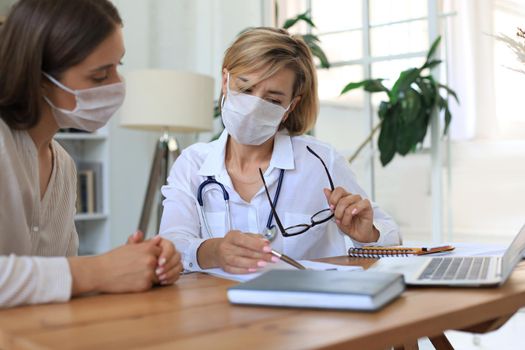 Middle aged female doctor therapist in consultation with patient in office