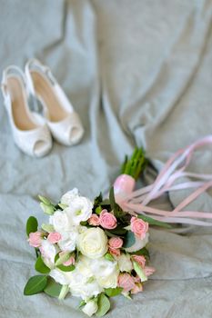Isolated bouquet of flowers with shoes at photo studio in blue background. Concept of floristic art and photo session.