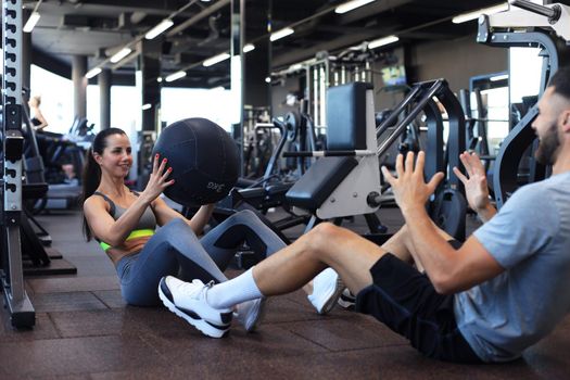 Fit and muscular couple exercising with medicine ball at gym