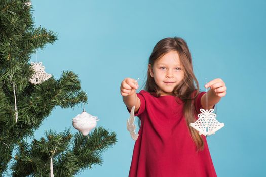 Christmas, childhood and people concept - little girl decorating the christmas tree.