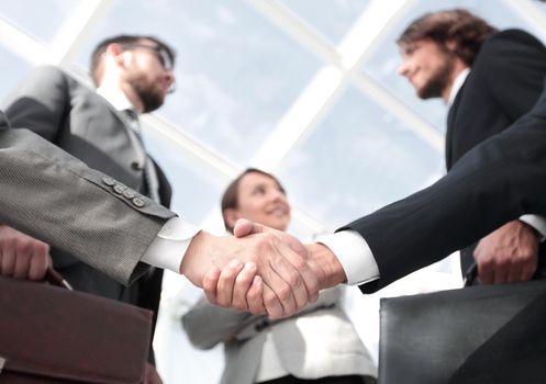 smiling business team looking at a business handshake partner.