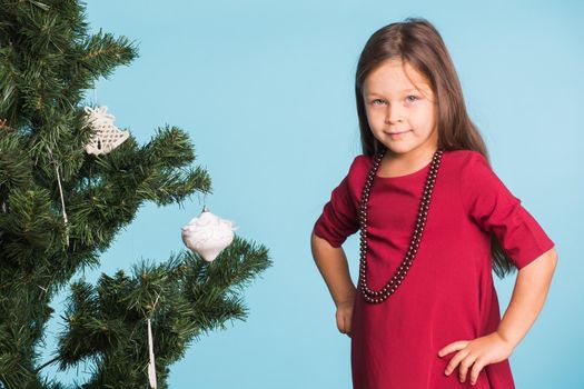 Little girl with christmas tree on blue background.