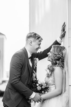 bride and groom are talking standing near the city building. holidays and events
