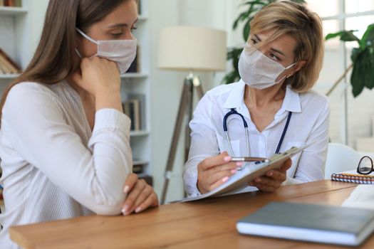 Middle aged female doctor therapist in consultation with patient in office