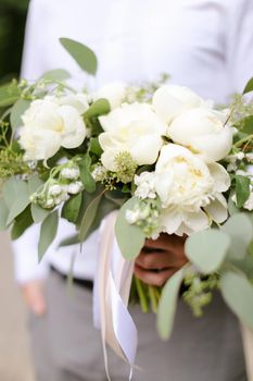 Close up bouqet of flowers in groom hands. Concept of bridal photo and floristic art.