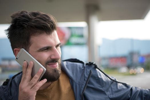 handsome young casual business man with beard using cell phone and smile outdoor on city street