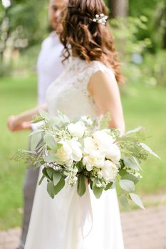 Caucasian happy bride walking with groom and bouquet of flowers. Concept of bridal photo session and married couple.