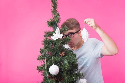 Christmas and holiday concept - Portrait of smiling man with Christmas Tree on pink background.