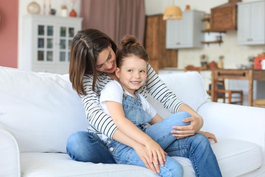 Happy loving mom hugging little daughter, spend time together at home
