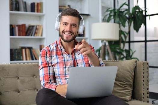 Smiling businessman greeting colleagues in video conference and negotiating distantly from home