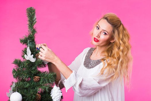 Christmas and holiday concept - Portrait of smiling beautiful woman with Christmas tree over pink background.