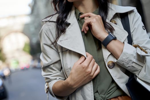 Cropped shot of a fashionable woman in grey coat standing on the city street. Fashion, people lifestyle concept