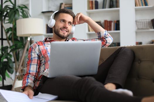 Smiling businessman greeting colleagues in video conference and negotiating distantly from home