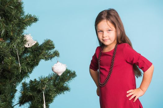 Little girl with christmas tree on blue background.