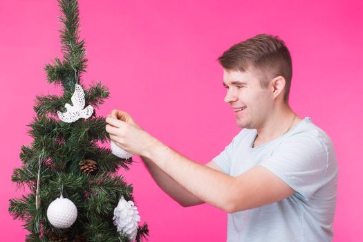 Christmas and holiday concept - Portrait of smiling man with Christmas Tree on pink background.