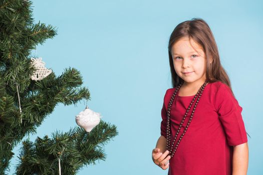 Little girl with christmas tree on blue background.