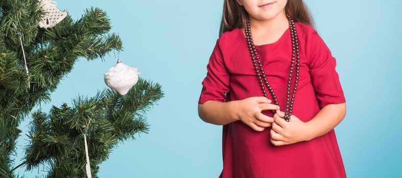 Little girl with christmas tree on blue background.