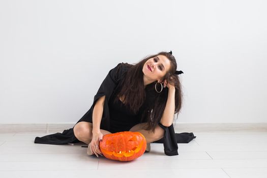 Halloween and holidays concept - Witch woman with Jack O'Lantern pumpkin.