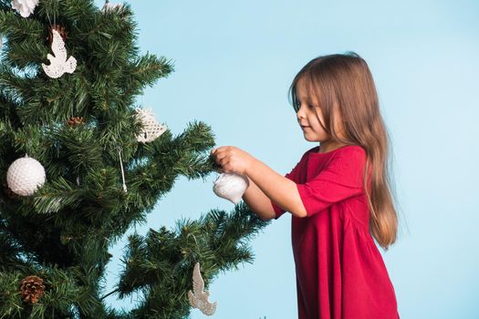 Little girl with christmas tree on blue background.