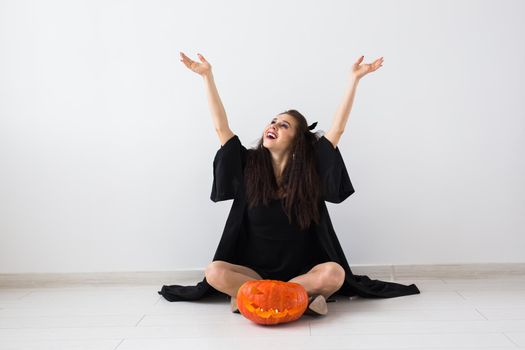 Cute woman in halloween style clothes with pumpkin in hands.