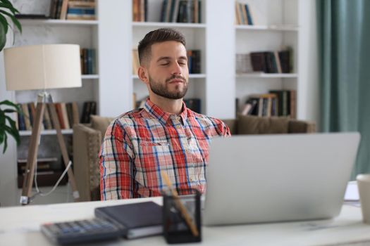 Smiling handsome businessman relaxing at home office