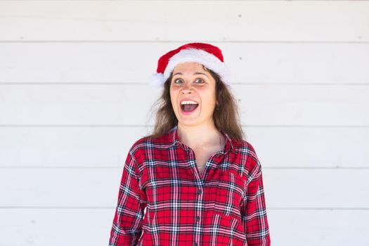 Christmas, holidays, people concept - young woman in santa hat and shirt smiling over the white background.