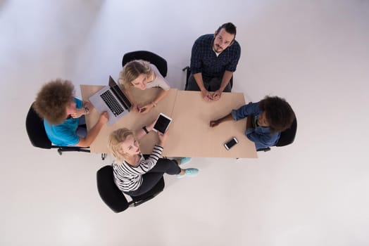 Multiethnic startup business team on meeting in modern bright office interior brainstorming, working on laptop and tablet computer top view